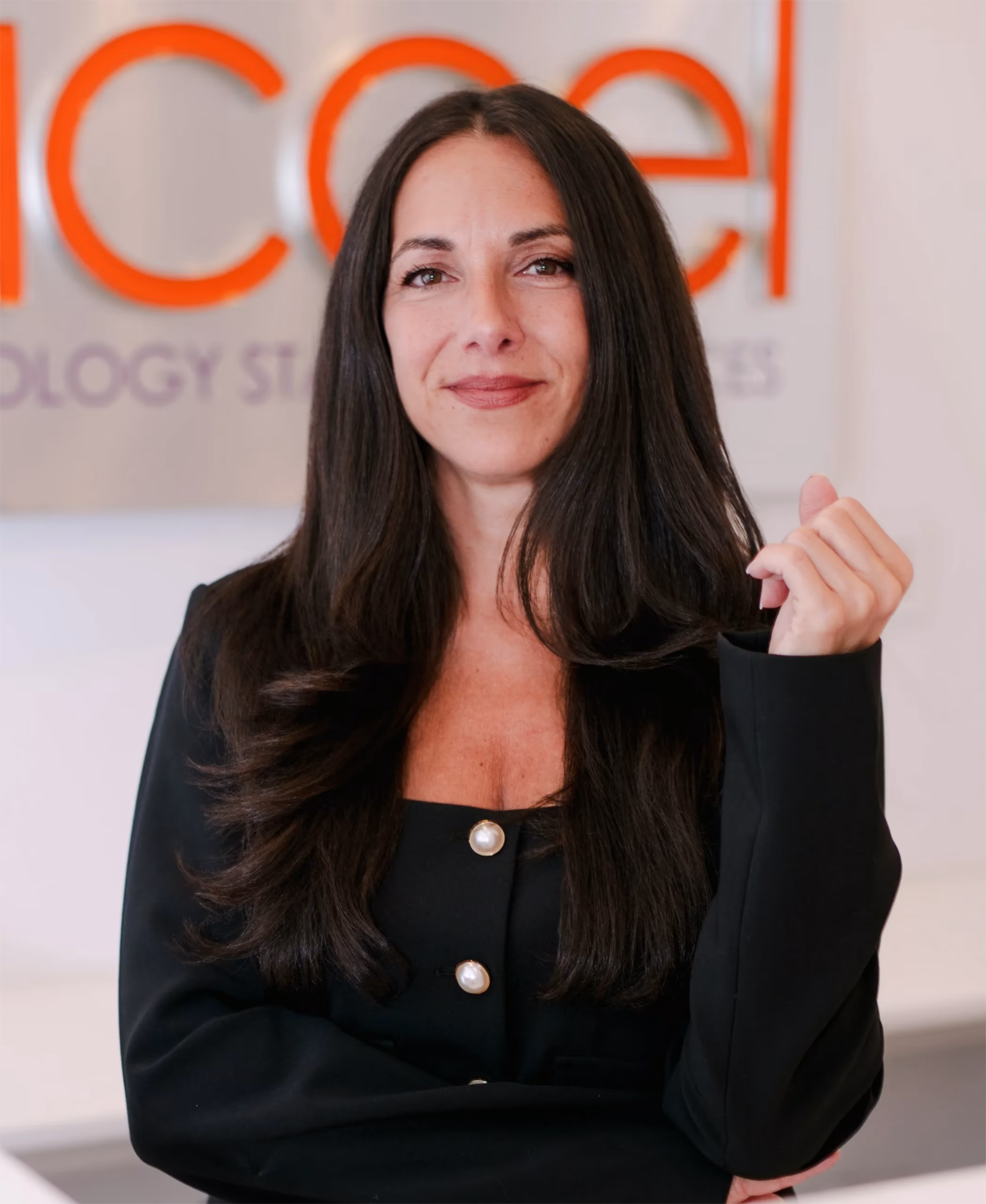 professional-headshot-branded-office-signage-itaccel. IT Accel team member in a black blazer standing in front of the company's branded office signage