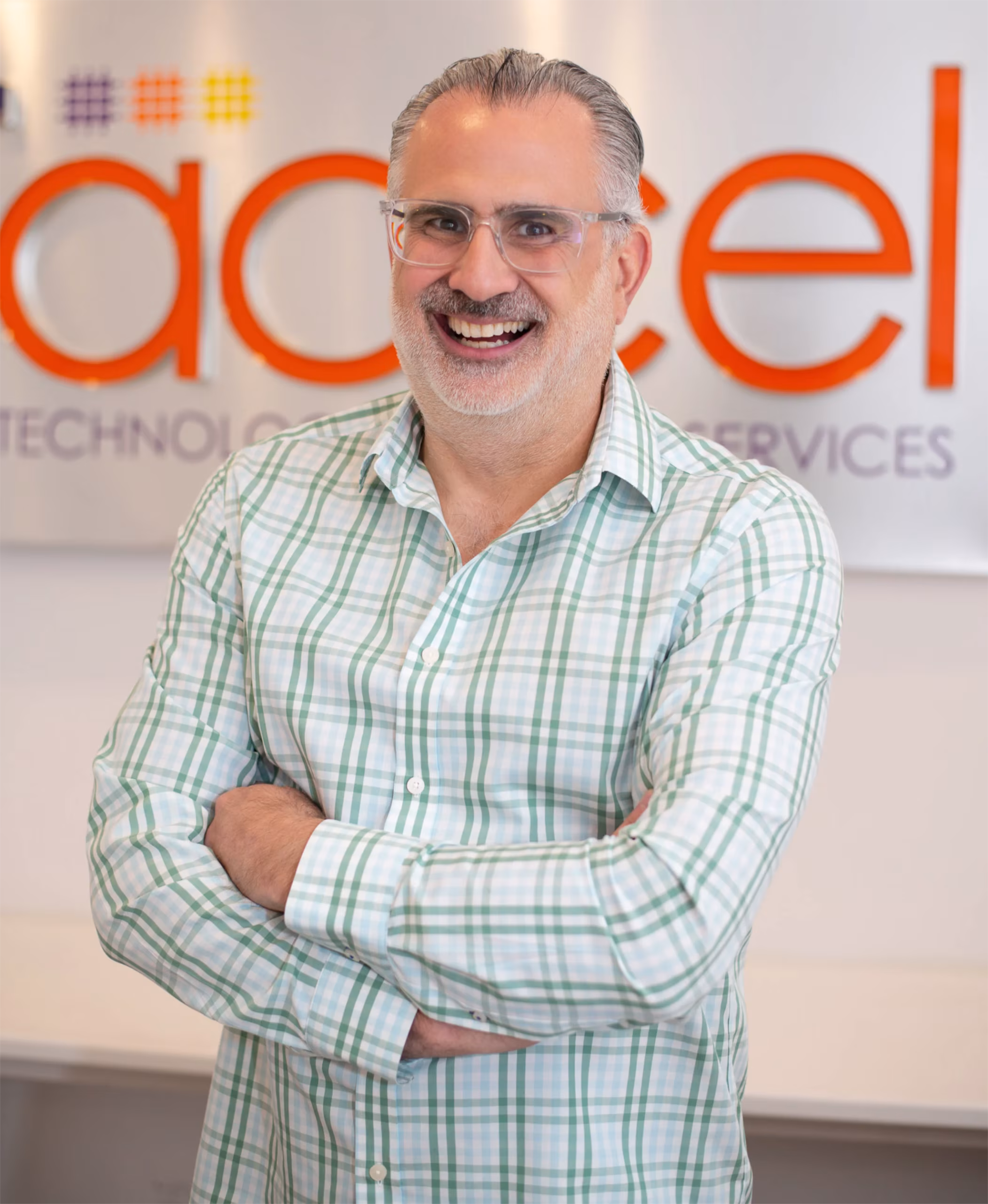 smiling-team-member-office-signage-itaccel. Smiling IT Accel team member with arms crossed in front of the company's New York office signage